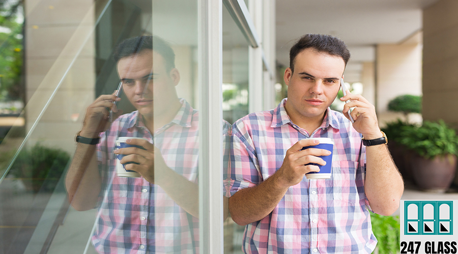 Brutal handsome man in checkered shirt drinking coffee outdoors Brutal handsome man in checkered shirt drinking coffee outdoors. Serious brunette young guy talking on mobile phone and looking at camera. City break concept