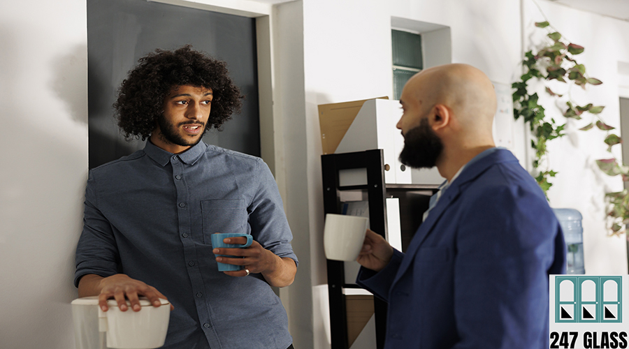 Two young arab colleagues drinking coffee and having friendly chat in business office. Company coworkers discussing work and enjoying tea during break in coworking space workplace