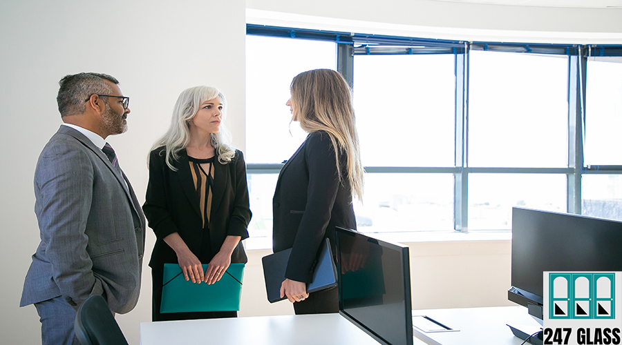 Experienced colleagues standing in office room Experienced colleagues standing in office room and looking at each other. Professional content CEO and pretty businesswomen discussing work project. Business, communication and corporation concept