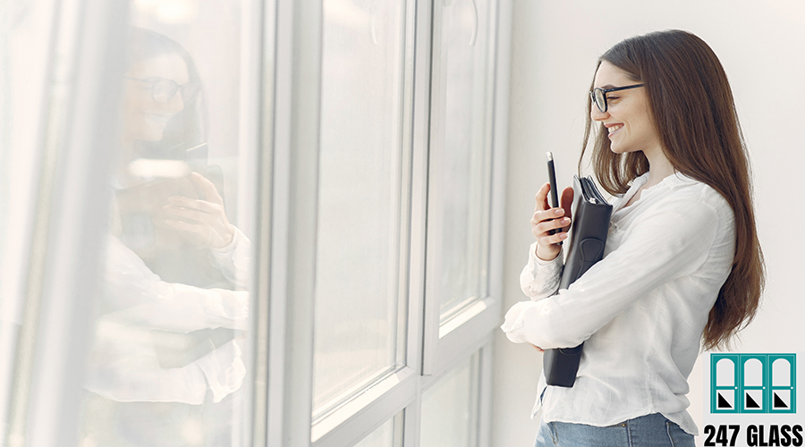 Girl standing in the office with a folder Girl in a office. Woman in a white shirt. Lady in a glasses standing by the window.