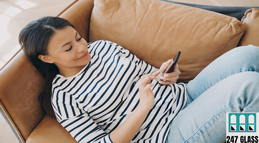 Happy woman using modern mobile apps on smartphone, shopping in online store lying on sofa at home Happy woman using modern mobile apps on smartphone lying on sofa at home. Female housewife holding phone, shopping in online store, checking social networks news on couch. E-commerce concept.