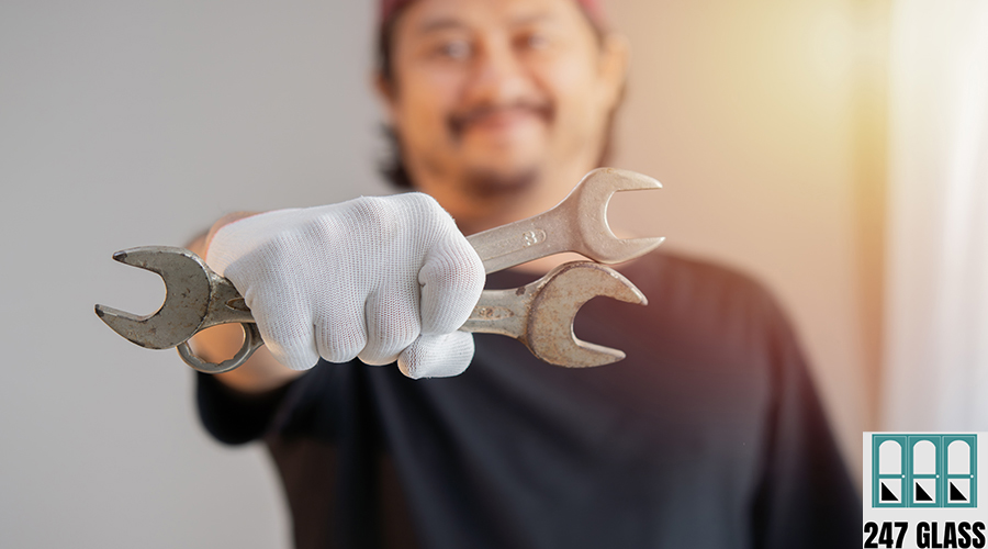 Man's hand wearing white cloth gloves and holds a spanners over commercial door service
