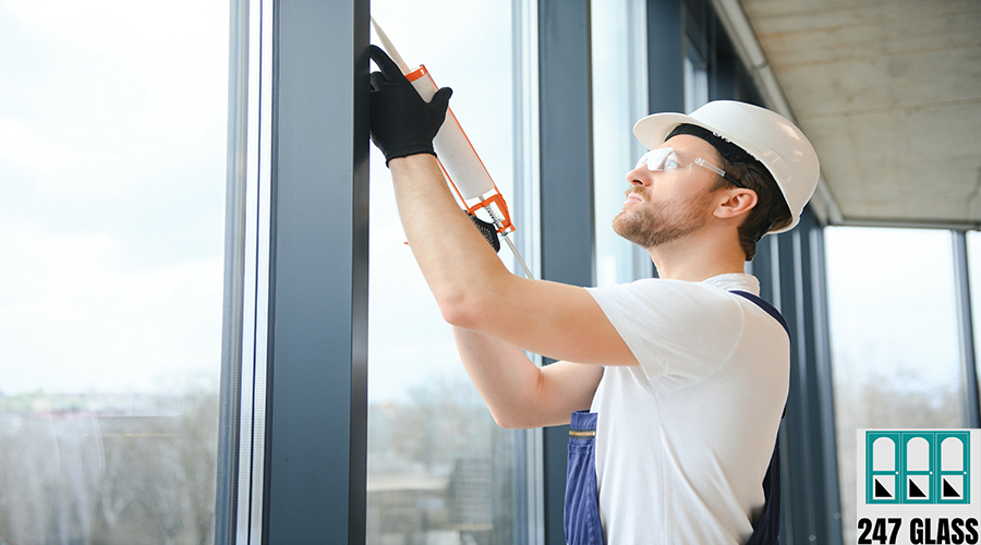 Workman in overalls installing or adjusting plastic windows in the living room at home broken glass replacement