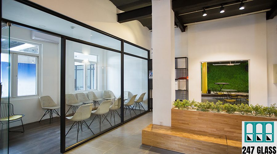 Nobody in office lobby with wooden bench. White wall with column and shelves. Green plants as part of interior. Many chairs behind glassy wall. Business center concept
